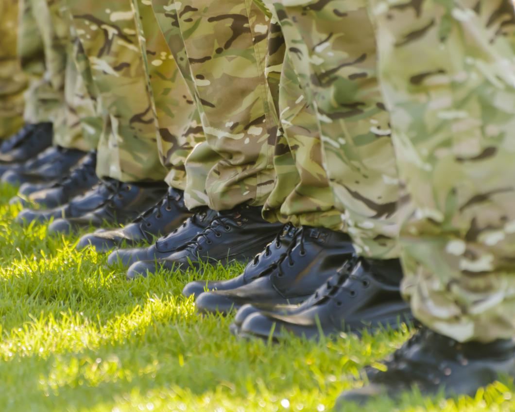 Soldaten staan op een rij met hun laarzen op een groen grasveld