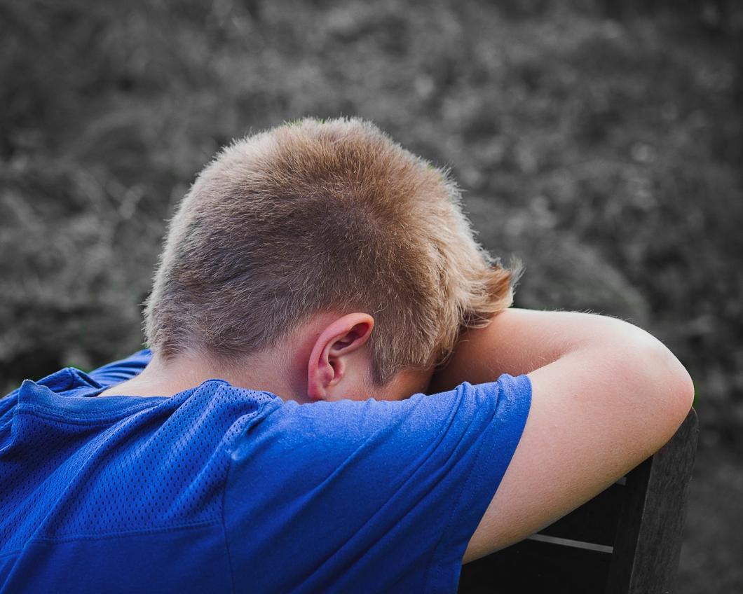 Een jongen staat huilend met zijn hoofd in zijn armen