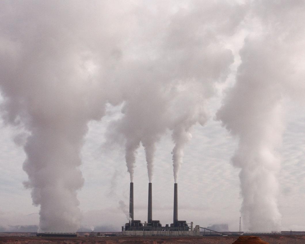 Een fabriek stoot grote witte rookpluimen uit