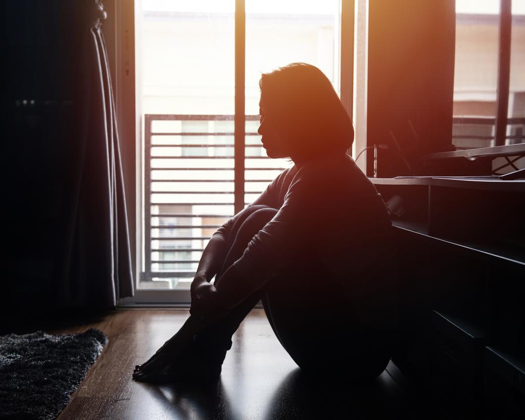 Vrouw zit thuis op de grond in het donker