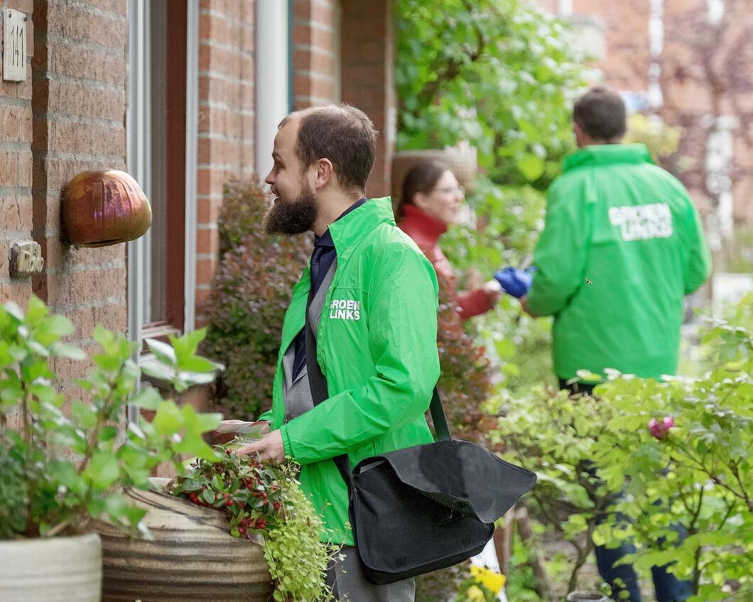 Enthousiaste vrijwilligers in een GroenLinks-jas bellen aan in de buurt om met de bewoners te spreken over wat zij willen dat de politiek voor ze doet.